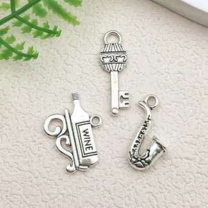 Detailed close-up of antique silver alloy charms featuring wine bottle, key and saxophone