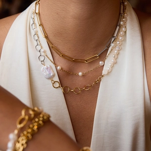 Close-up of layered necklace set featuring baroque pearls and gold-plated paperclip chains