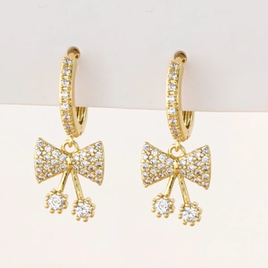 Close-up of golden bow earrings with micro-pave zircons and round crystal drops