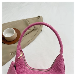 Detailed shot of pink woven shoulder bag with gold zipper on white wrinkled fabric