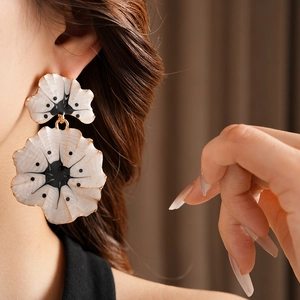 Gros plan de boucles d'oreilles ginkgo vintage avec pétales blancs et bords dorés
