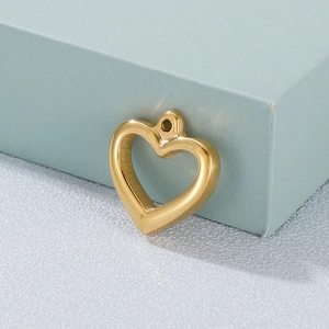 Polished gold hollow heart pendant made of premium stainless steel on a blue prop
