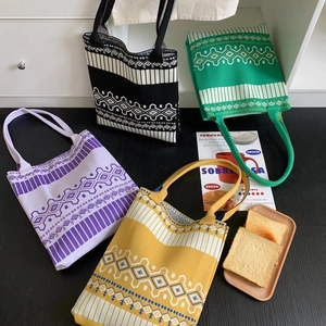 Ethnic knit tote bags with geometric patterns in four colors on a wooden surface