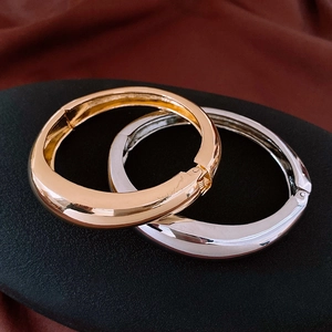 Détail de bracelets larges articulés en métal doré et argenté sur fond de soie