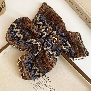 Détail macro d'un chouchou tricoté rétro avec motif zigzag et étiquette de marque tissée
