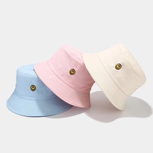 Stack of colorful cotton bucket hats with embroidered yellow smiley faces for outdoor sun protection