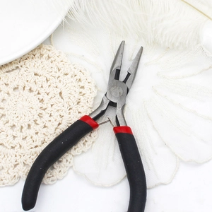 Detail of professional jewelry pliers with red and black handles on a soft feather background