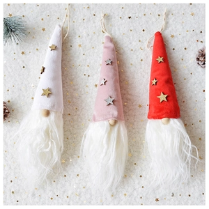 Close-up of plush Christmas gnome ornaments with sequined hats on snowy background