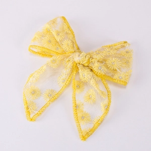 Detail of yellow tulle bow hair clip featuring delicate daisy embroidery and stitched edges