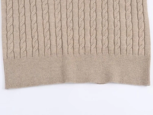 Close-up of cable knit pattern and ribbed hem on beige knitted polo sweater