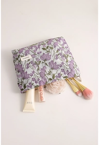 Detailed embroidery of purple flowers on a light blue canvas makeup bag for travel