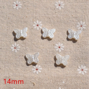 Macro detail of 14mm cream butterfly faux pearl charms for DIY jewelry making
