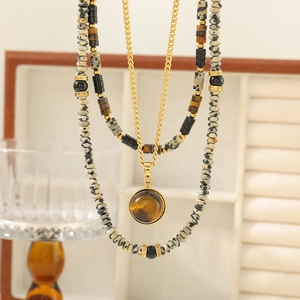 Detail of layered natural stone necklaces with tiger eye pendant and golden spacer beads