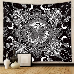 Detail of bohemian black and white tapestry with butterfly, moon, and mushroom patterns