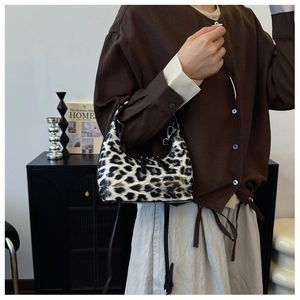 Detailed view of glossy leopard print crossbody bag styled with autumn cardigan