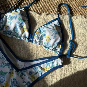 Detailed close-up of a blue floral bikini featuring fabric labels and textured beach mat