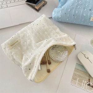 Vue détaillée d'une trousse à maquillage en dentelle blanche avec paillettes argentées