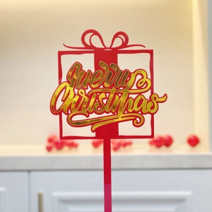 Detail of red and gold acrylic Merry Christmas cake topper in gift box shape