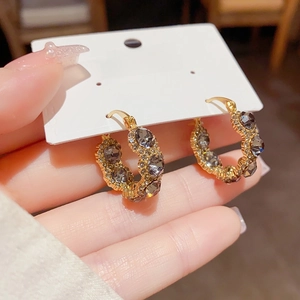 Detailed shot of gold-plated hoop earrings with grey cat-eye stones in a vintage style