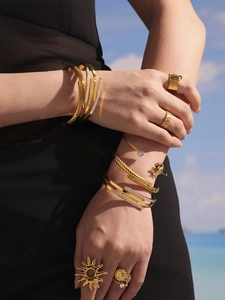 Detailed view of layered 18K gold-plated bracelets and rings with sparkling zircons