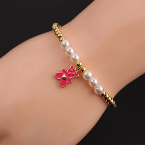 Detail von Goldperlen und Perlenarmband mit einem pinkfarbenen Emaille-Bärenanhänger