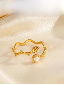 Detail of a gold leaf ring featuring a white pearl inlay on soft silk fabric