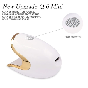 Macro view of the Q6 Mini nail lamp showing the gold touch button and portable design