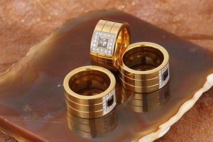 Detail of gold titanium rings with white and blue cubic zirconia on agate stone
