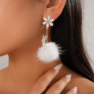 Close-up of Christmas deer earrings with snowflake studs and white pom-pom pendants
