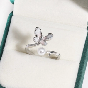 Detail of the butterfly pearl ring with pink enamel in a luxury green jewelry box