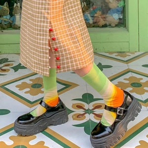 Dettaglio di calzini a righe colorate abbinati a scarpe Mary Jane nere con plateau