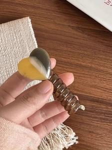 Detail of yellow and brown heart-shaped resin hair clip with transparent spring