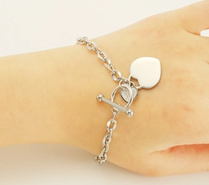 Détail du bracelet en acier argenté avec pendentifs cœurs, zircons et fermoir à bascule