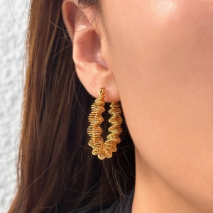 18k gold plated stainless steel wave spring hoop earrings worn by a model in close-up view