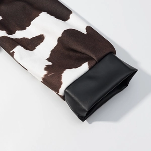 Detail van imitatiebontmouwen met koeienprint en zwarte PU-lederen manchet