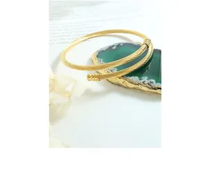 Detailed close-up of golden cable twisted cuff bracelet on a green agate stone display