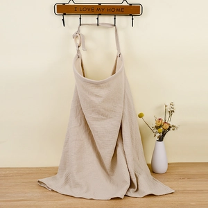 Detailed texture of beige cotton gauze nursing cover with adjustable neck strap