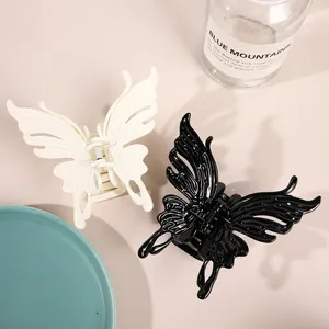 Detail of large butterfly hair claws in black and cream with a glossy hollow wing design