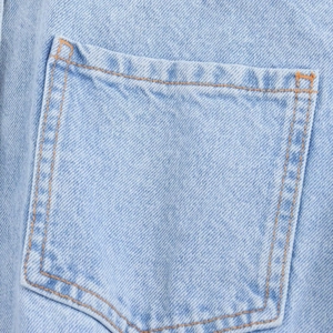 Detail shot of light blue denim fabric texture and double-stitch pockets on the romper
