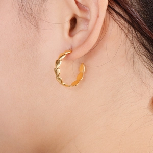 Close-up of a gold heart-shaped hoop earring worn by a model in a high-quality lifestyle shot