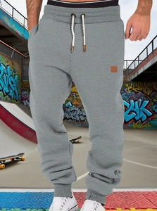 Detail of dark grey joggers with elastic waistband and white drawstring in a street setting