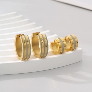 Dettaglio di ampi orecchini a cerchio in acciaio inossidabile oro e argento satinato