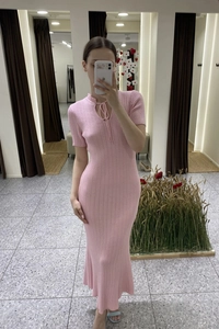 Dettaglio dell'abito in maglia rosa slim con scollatura a goccia e lacci decorativi