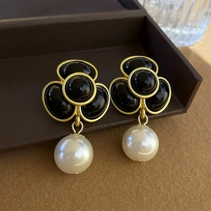 Detail of vintage gold clover earrings with black inlay and a round white pearl pendant