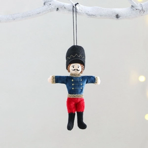 Blue nutcracker soldier plush Christmas ornament with gold embroidery on white branch
