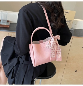 Pink litchi texture bucket bag with patterned scarf detail worn by a model in black
