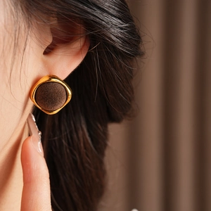 Gros plan de boucles d'oreilles rondes vintage avec velours marron et bordure dorée