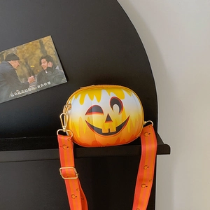 Detail of pumpkin-shaped crossbody bag with festive smiley face and striped strap