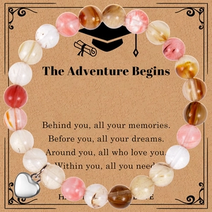 Macro detail of natural agate bead bracelet with silver heart pendant on graduation gift card