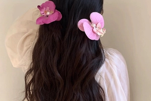 Detail of orchid hair clips with pearls on dark wavy hair for a French vintage look